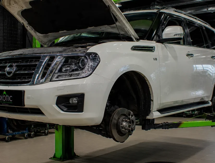 SUV raised on a hydraulic lift with a wheel removed for rim painting at the System X Car Polish workshop in Al Quoz, Dubai