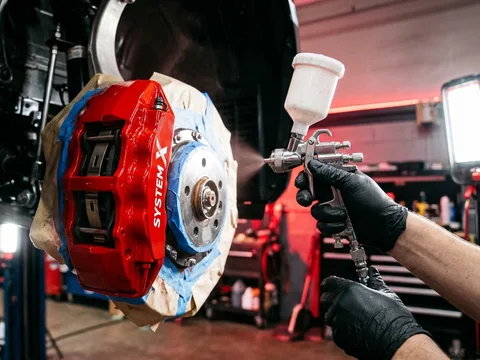 Brake caliper being spray painted red at the System X Car Polish workshop in Dubai