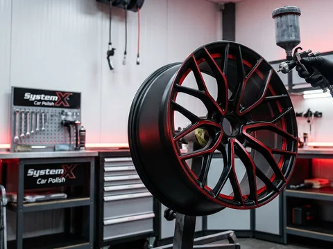 Technician spray painting an alloy wheel at the System X Car Polish workshop in Dubai